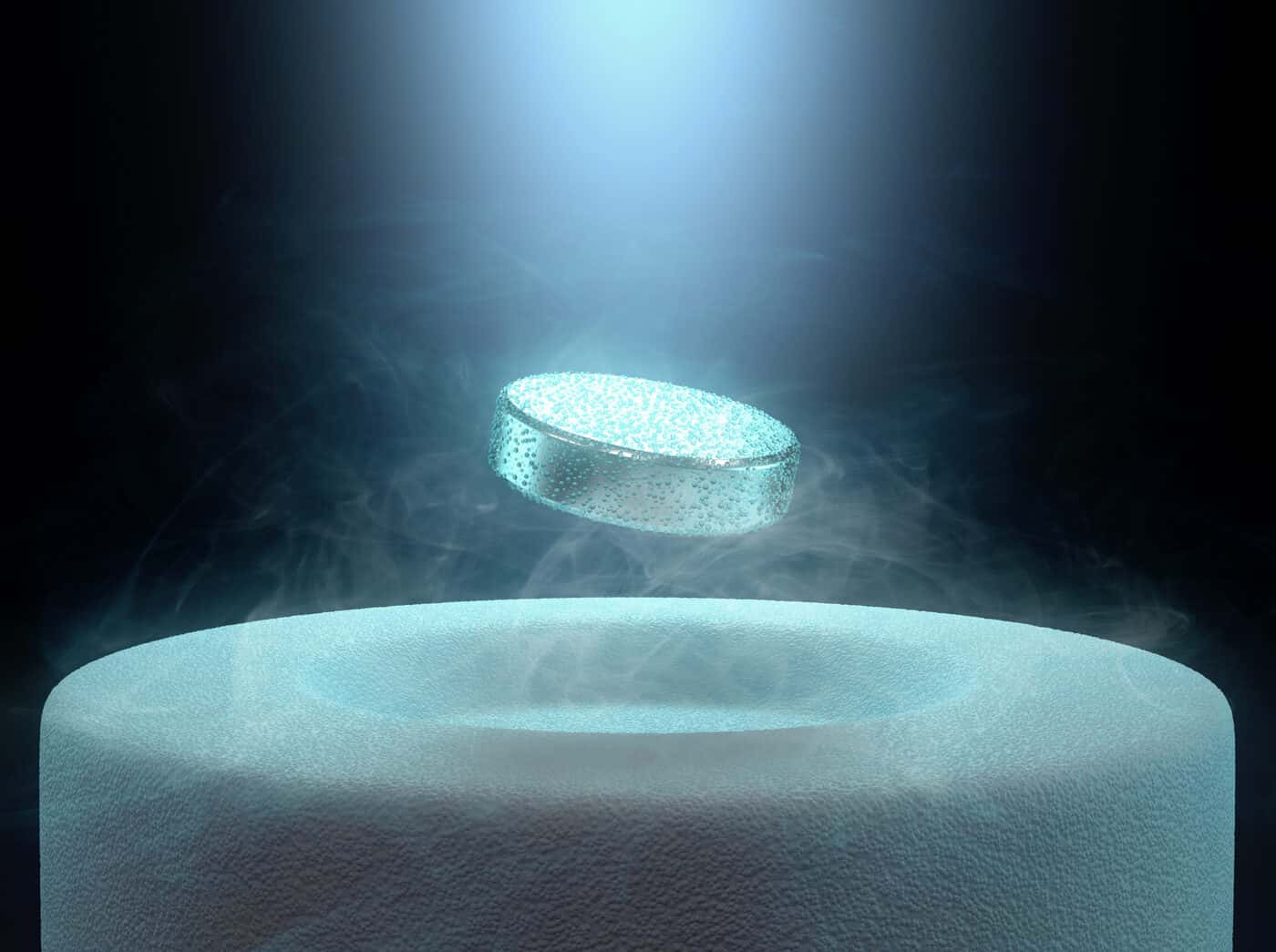 A superconductor disk levitating in a cloud of cryogenic vapor above a chilled base, held aloft by the expulsion of the magnetic field